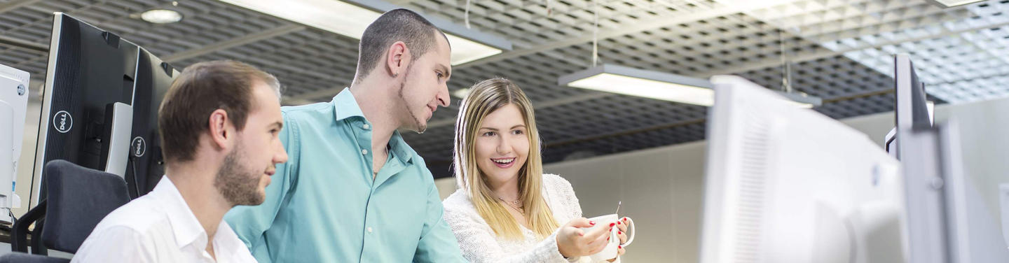 Büromanagement am Flughafen München Drei Personen arbeiten im Team am Computer im Büro des Flughafens München und besprechen Inhalte auf dem Monitor; freundliche, kooperative und professionelle Arbeitsatmosphäre.