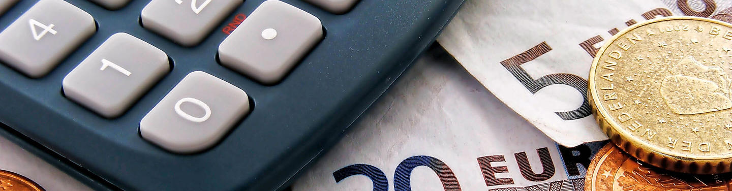Postbank Service at Munich Airport Close-up of a calculator next to euro banknotes and coins as a symbol of Postbank and financial services at Munich Airport; the image appears neutral, clear, and informative.
