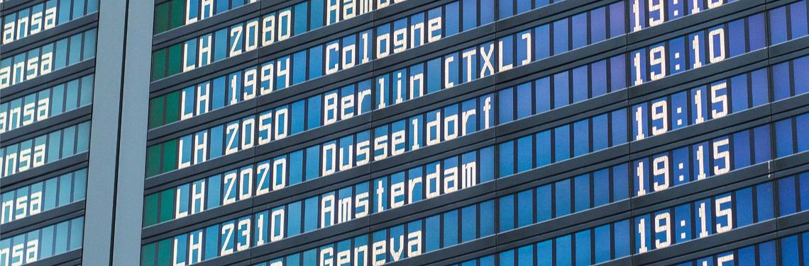 Flight plan Close-up of a blue digital flight information display at Munich Airport showing flight numbers, destinations such as Berlin and Amsterdam, and departure times; the display appears clear, well structured, and easy to read.