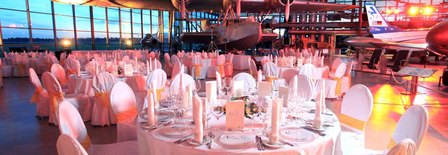 Gala Großer Saal mit elegant eingedeckten Rundtischen, weißen Hussen und stilvoller Beleuchtung. Der Raum wirkt professionell vorbereitet für eine Gala, Hochzeit oder Firmenfeier – festlich, großzügig und hochwertig.