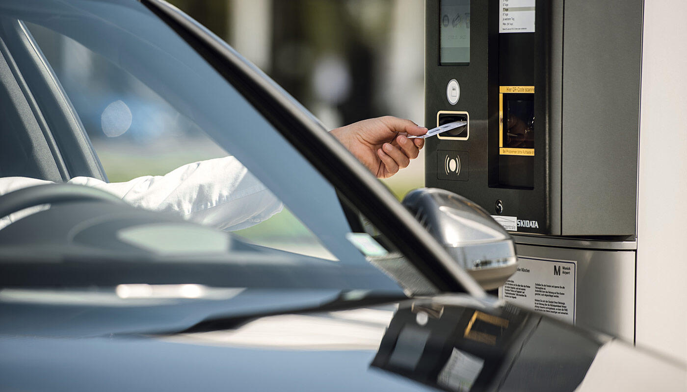 Parking at the AirportAcademy Man pulls a parking ticket from the machine through the open car window.