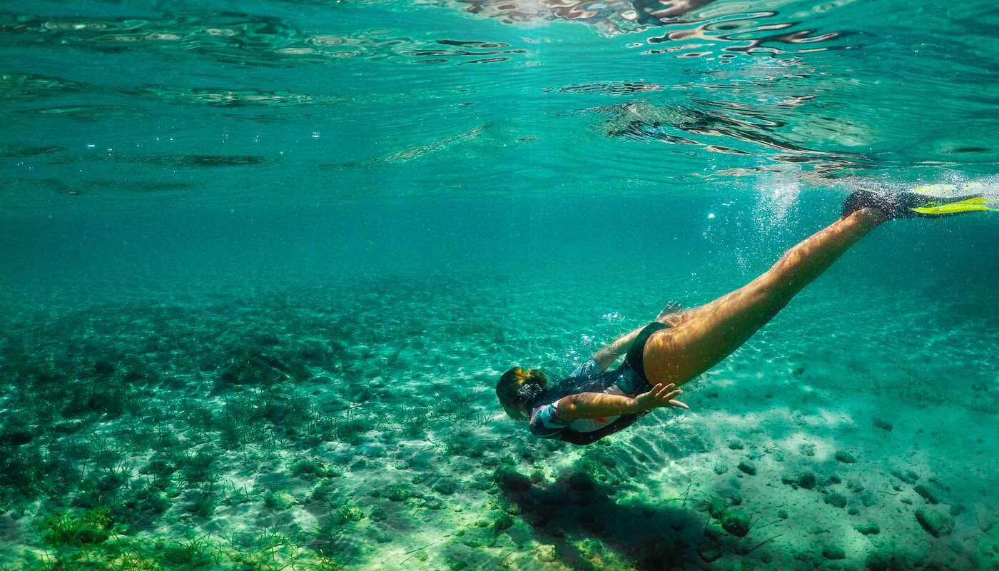 Frau taucht im Meer Frau mit Schwimmflossen taucht im Meer