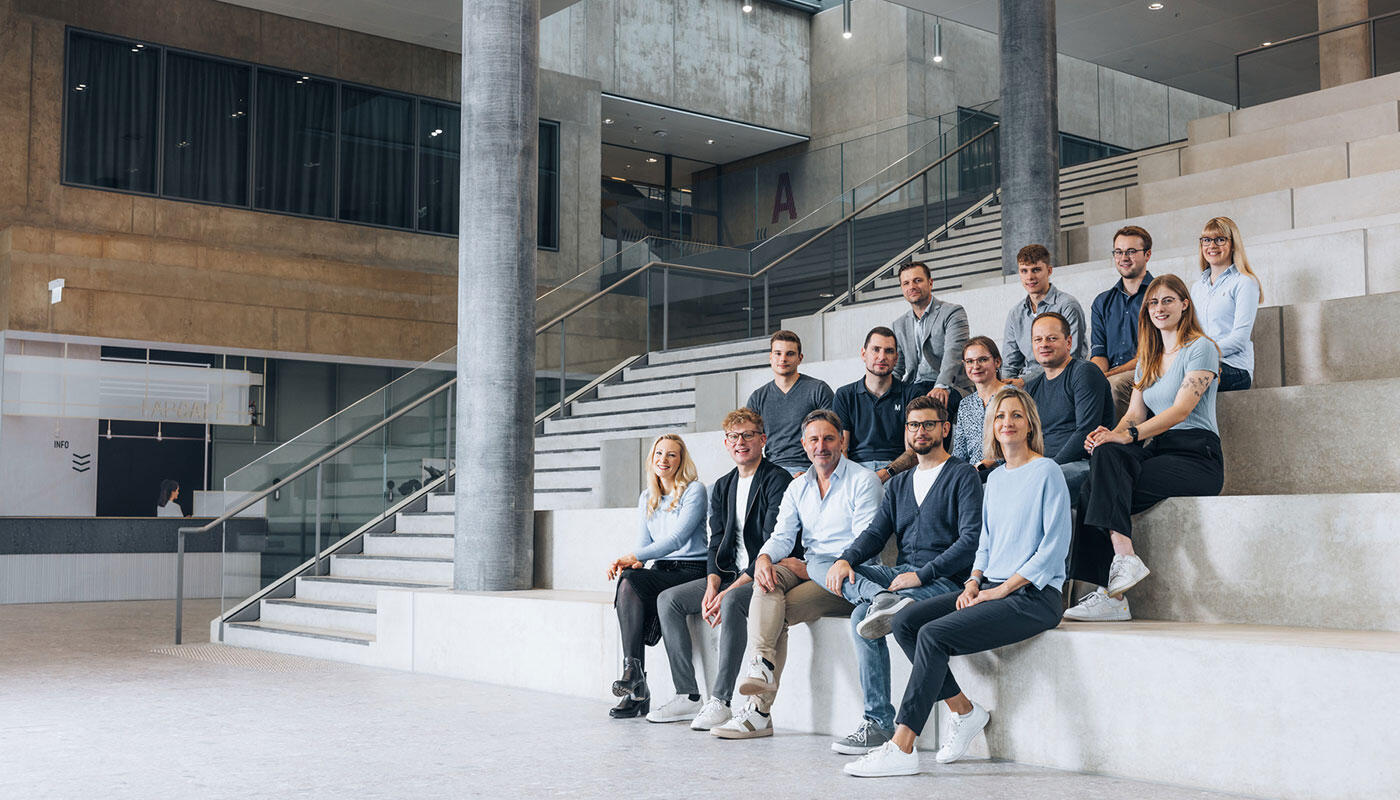Gruppenbild Mitarbeiter der FMG-IT IT Mitarbeitende sitzen auf einer Treppe im LabCampus
