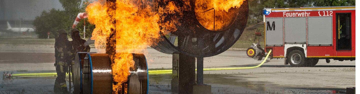 Gemeinsam gegen das Feuer: Einsatz am Flugzeug Feuerwehrleute löschen brennendes Flugzeug mit Feuerwehreinsatzwagen im Hintergrund