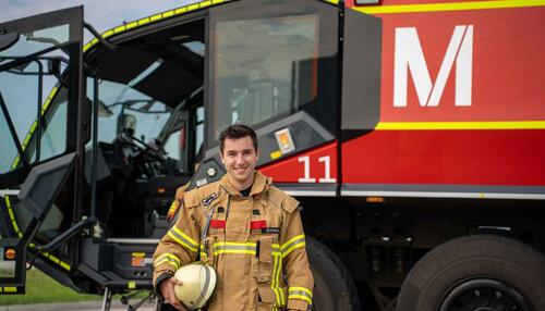 Feuerwehrmann vor Einsatzwagen trifft im Alarmfall schnelle Entscheidungen