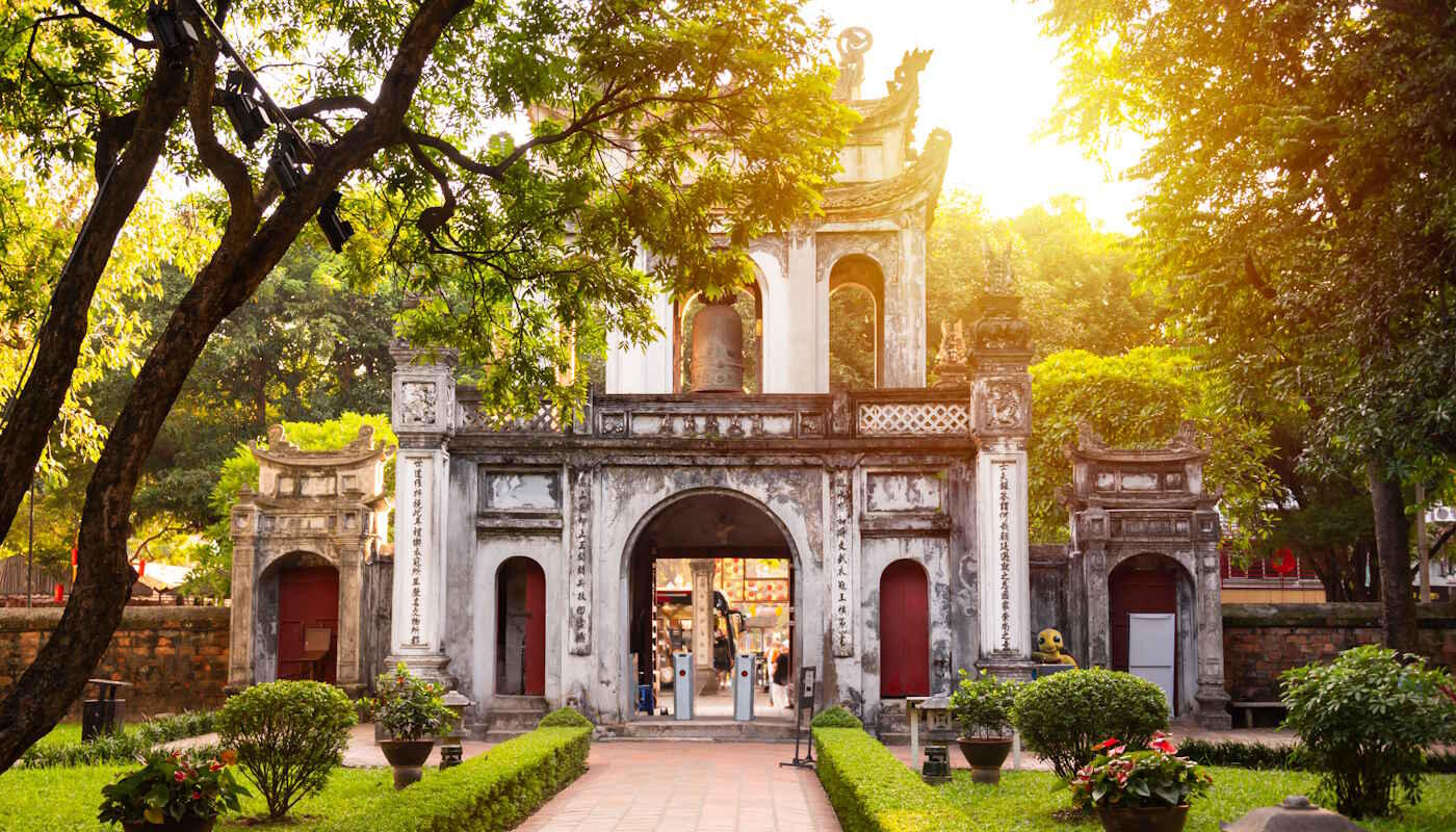 Literaturtempel in Hanoi, Vietnam Der Literaturtempel in Hanoi, Vietnam, umgeben von einer grünen Gartenanlage mit Bäumen. Die Sonne scheint, und ein gerader Weg führt direkt zum Tempel.