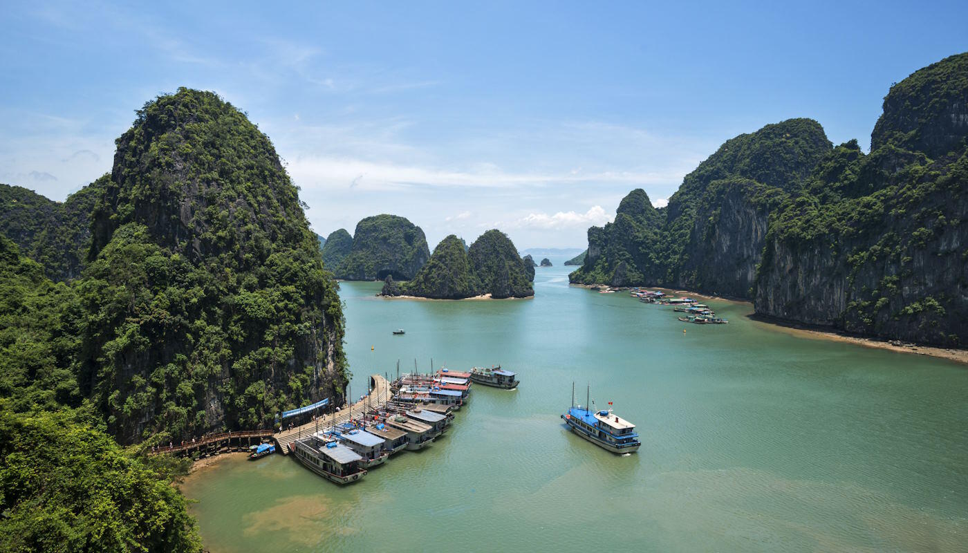 Halong Bucht in Vietnam Die Halong-Bucht in Vietnam mit türkisfarbenem Wasser. Rechts und links ragen bewachsene Felsen mit Büschen und Bäumen aus dem Wasser.