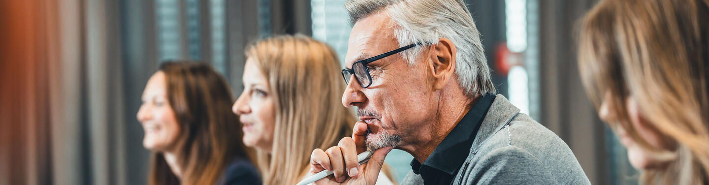 AirportAcademy Schulungsteilnehmer Vier Schulungsteilnehmer sitzen an einem Tisch und blicken zum Trainer.