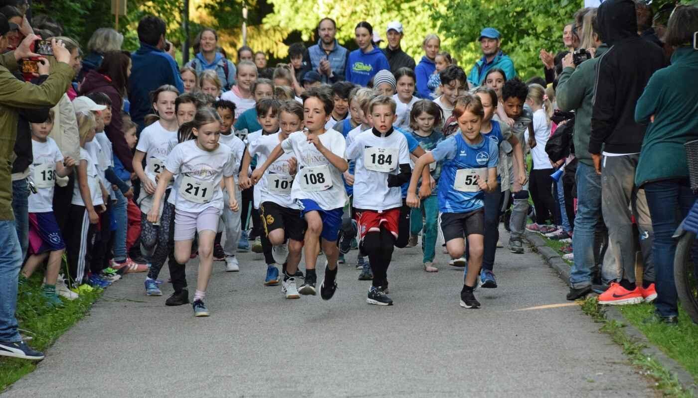Kids race at Weihenstephan Panorama Run A large group of children bursts into a race with energy and excitement, focused faces, spectators cheering along the path, a moment full of movement, community, and joy.