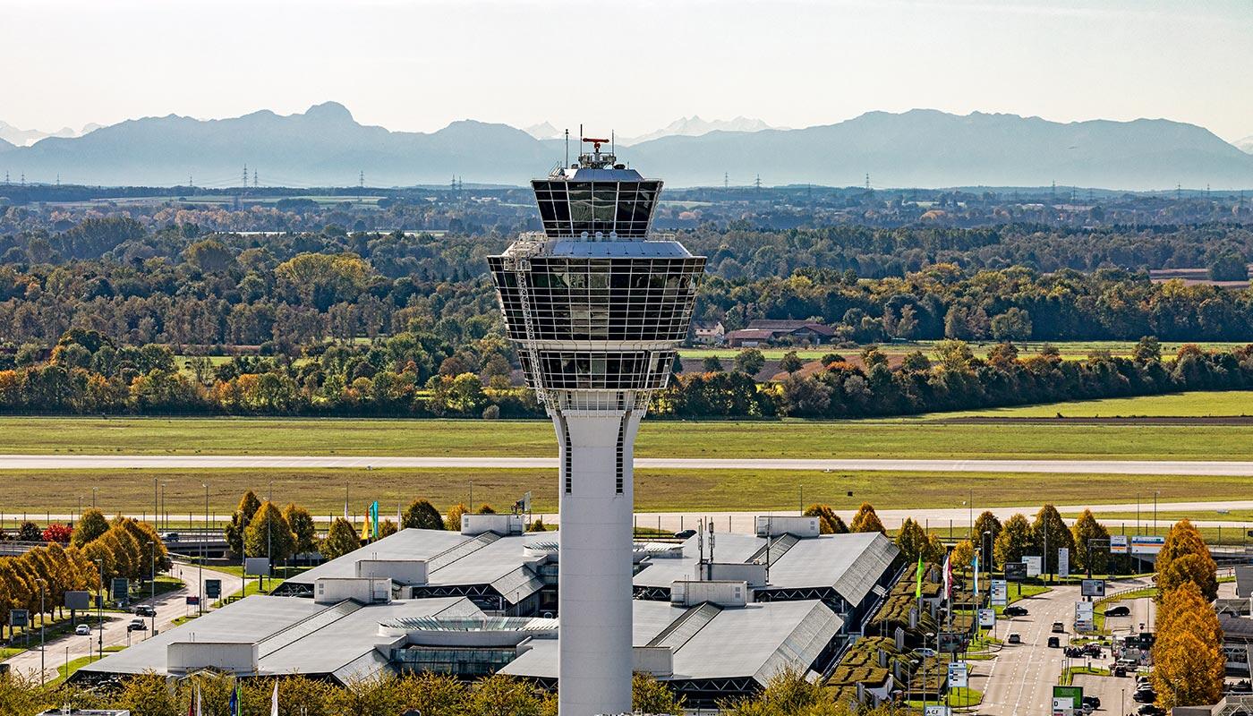 Standort im Herzen Bayerns Flughafen München Tower mit Bergen im Hintergrund