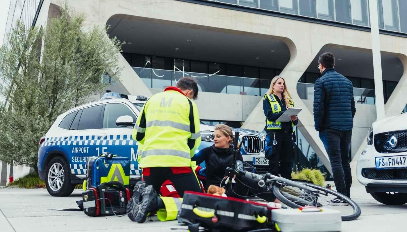 Emergency Medical Service Munich Airport – On-Site Response Emergency medical staff at Munich Airport assist an injured person beside a response vehicle. Medical equipment is laid out as the team provides professional care in front of the terminal.