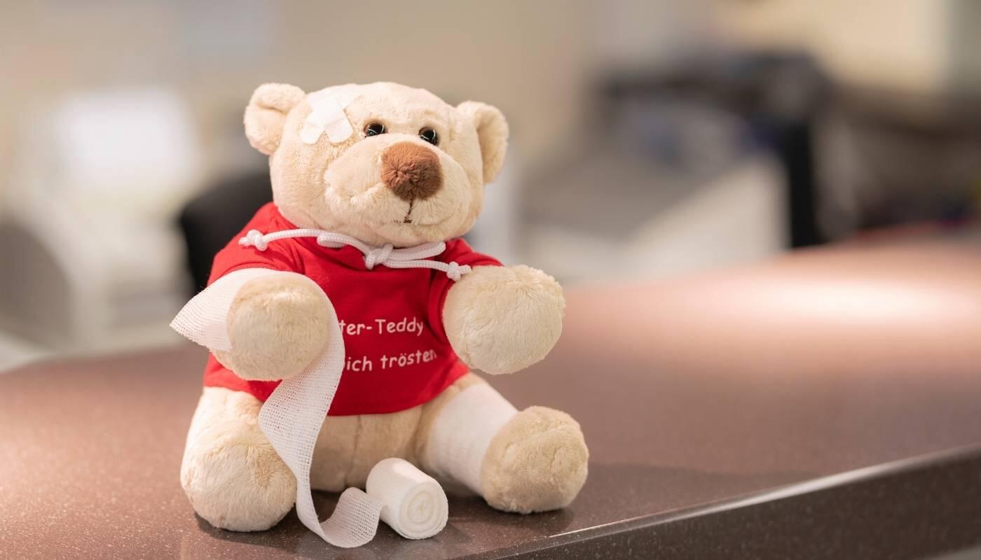Travel Medicine Munich Airport – Medical Services A teddy bear with a bandage sits on a treatment table at the travel medicine clinic at Munich Airport. The image symbolizes medical care, vaccinations, and health support for travelers.
