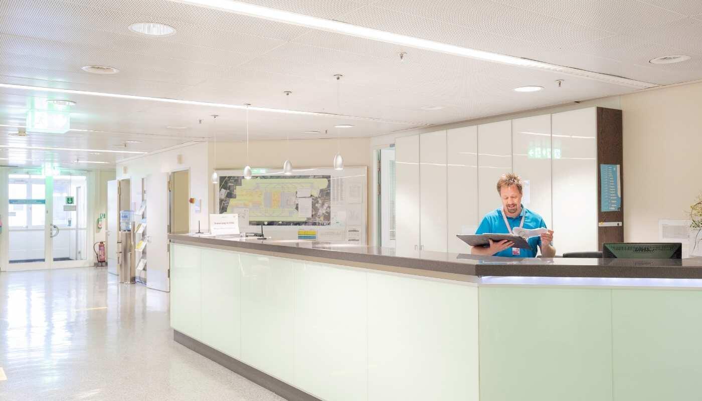 Travel Medicine Consultation & Vaccinations for departure – Airport Clinic Munich Reception area of the Airport Clinic at Munich Airport where medical staff assist travelers. The scene represents professional travel medicine consultations and vaccination services before departure.