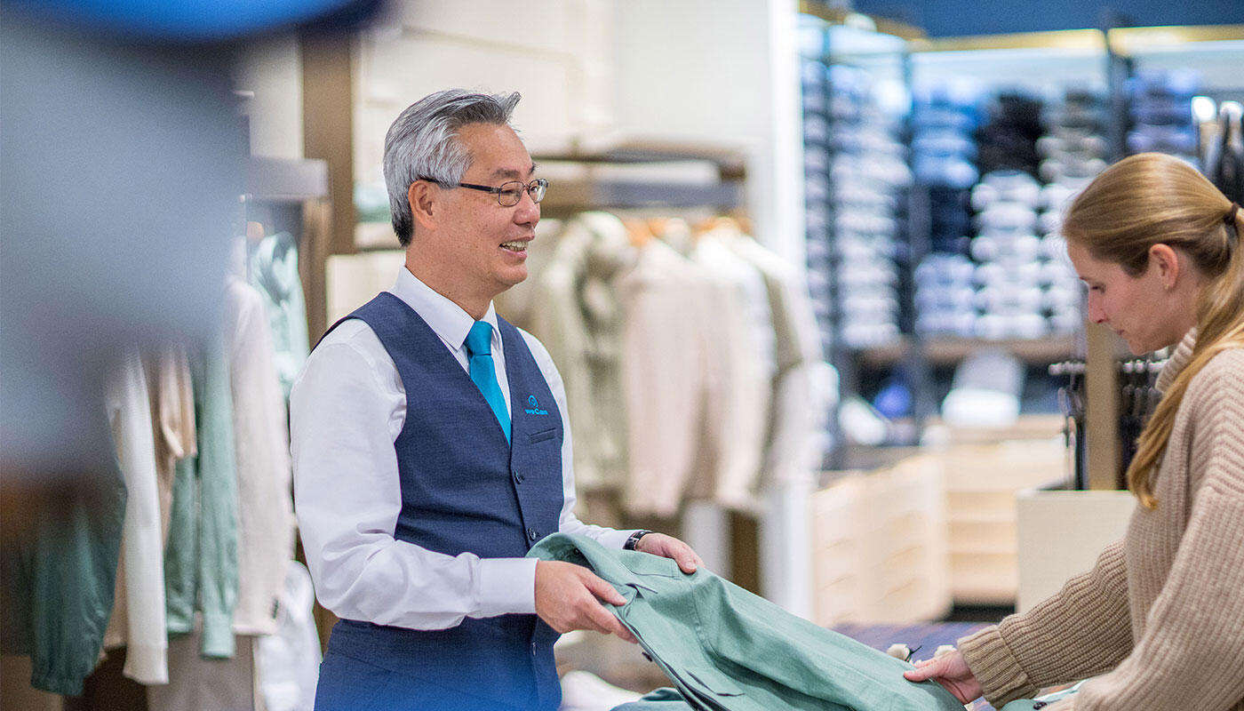Chinese Shopping Assistant Man sells jacket to a woman