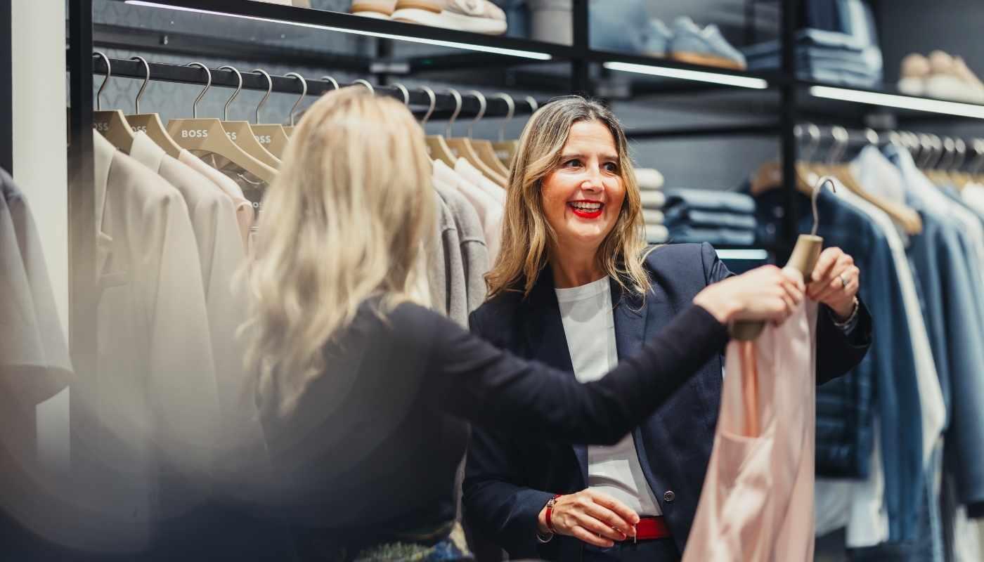 Freundliche Verkäuferin berät Kundin im Modegeschäft Eine lächelnde Verkäuferin berät eine Kundin herzlich und aufmerksam in einem stilvollen Modegeschäft – die Atmosphäre wirkt einladend, persönlich und vertrauensvoll.