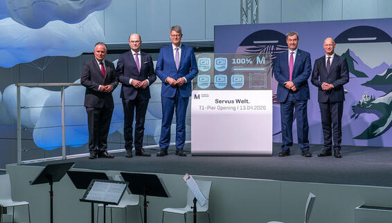Five men are standing next to an OLED display that shows 100% and has opened the pier