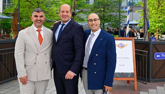 Meeting of the Bavarian-Arab Society at the Airbräu-Tenne Three men in suits are standing in front of an Airbräu sign