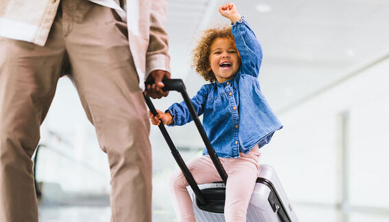 A child is sitting on a trolley and being pulled along by her father