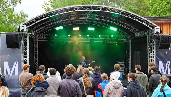 Live Music at the FünfSieben Festival – Munich Airport Supports Youth Culture A musician performs on the outdoor stage at the FünfSieben Festival while young festivalgoers enjoy the live concert. The illuminated stage and engaged audience create a memorable atmosphere filled with music, community, and the energy of a youth festival.