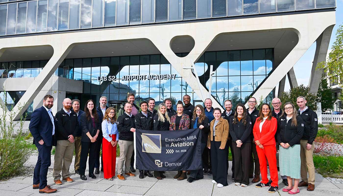 xecutive MBA in Aviation cohort Group photo of Executive MBA in Aviation participants standing in front of the Airport Academy building, holding a University of Colorado Denver program banner.